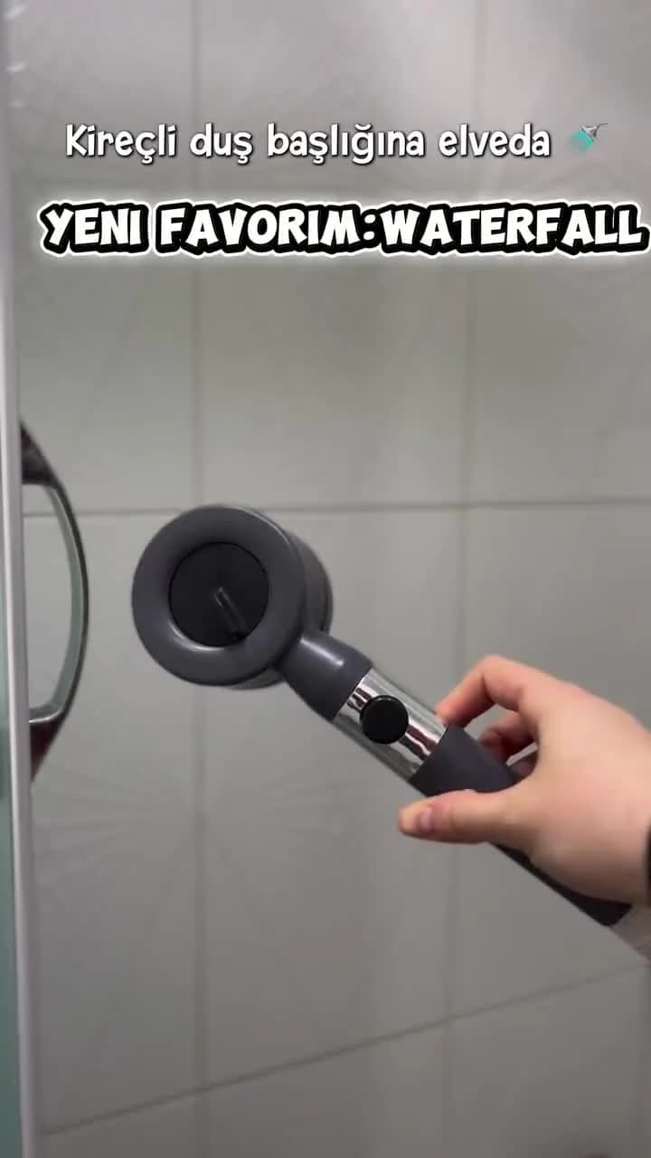 Videolu ürün şeridindeki duş başlığı videosunun kapağı: banyoda elde tutulan gri filtreli duş başlığı, üstte Kireçli duş başlığına elveda ve Yeni favorim: Waterfall yazıları.