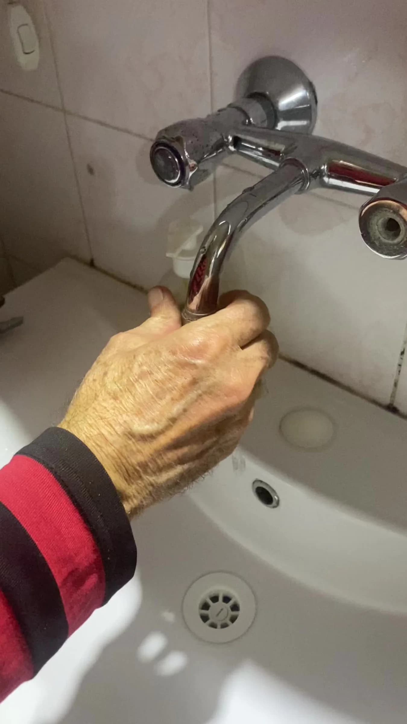 Videolu ürün şeridindeki kullanım videosunun kapağı: lavabo üzerindeki duvar musluğunu açan yaşlı bir el.