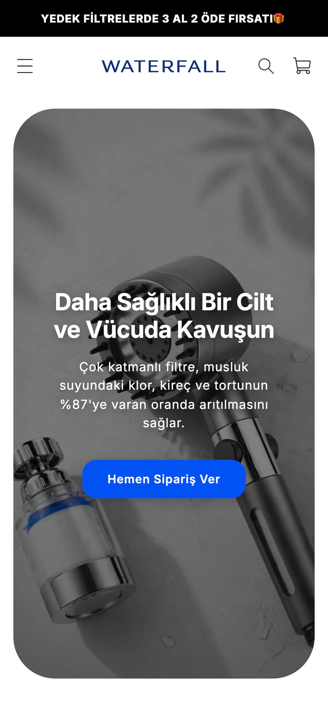 Waterfall'ın telefondaki ana sayfası: üstte siyah şeritte Yedek filtrelerde 3 al 2 öde fırsatı duyurusu, WATERFALL logosu, menü, arama ve sepet simgeleri; yuvarlak köşeli açılış alanında koyulaştırılmış duş başlığı ve musluk filtresi fotoğrafı üzerinde Daha Sağlıklı Bir Cilt ve Vücuda Kavuşun başlığı, çok katmanlı filtrenin klor, kireç ve tortunun %87'ye varan oranda arıtılmasını sağladığını anlatan cümle ve mavi Hemen Sipariş Ver düğmesi.