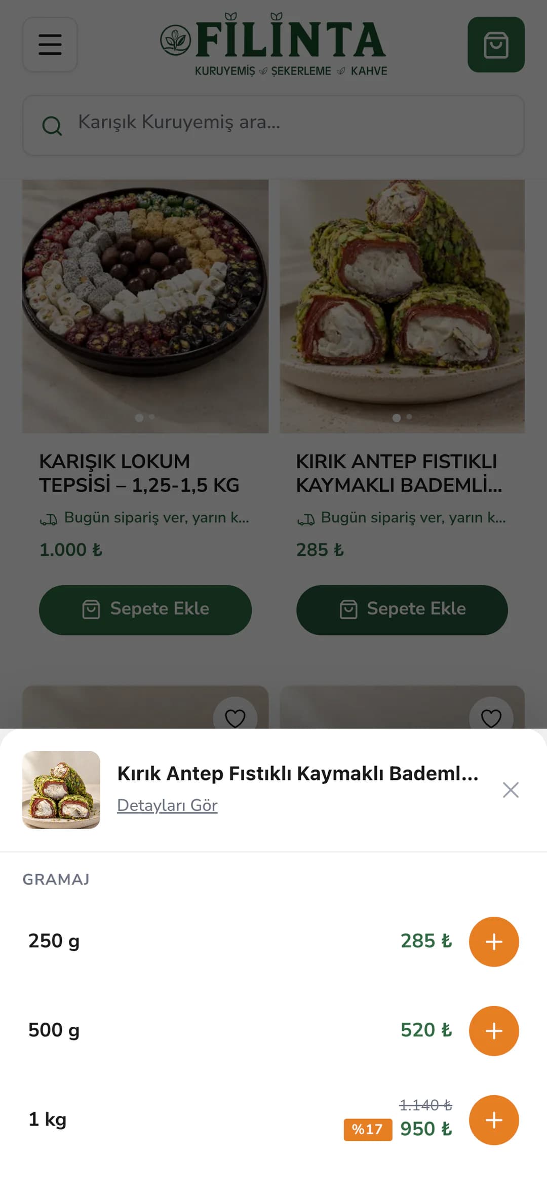 Ana sayfadaki ürün kartının Sepete Ekle düğmesiyle telefonda alttan açılan gramaj penceresi: Kırık Antep Fıstıklı Kaymaklı Bademli Sarma Lokum ve Detayları Gör bağlantısı; Gramaj başlığı altında 250 g 285 ₺, 500 g 520 ₺ ve %17 indirimli 1 kg 950 ₺ satırları, her birinde turuncu ekleme düğmesi; arkada kararmış vitrin.