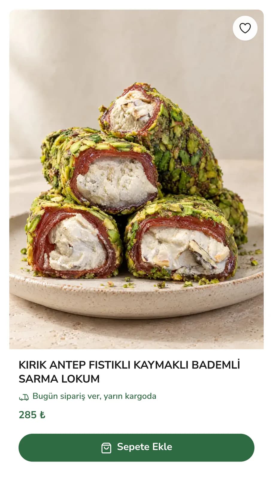 Lokum ve Şekerlemeler vitrinindeki ürün kartının yakın planı: tabakta Antep fıstığı kırığıyla kaplı kaymaklı sarma lokumlar, sağ üstte favori düğmesi; altında Kırık Antep Fıstıklı Kaymaklı Bademli Sarma Lokum adı, Bugün sipariş ver, yarın kargoda notu, 285 ₺ fiyat ve yeşil Sepete Ekle düğmesi.