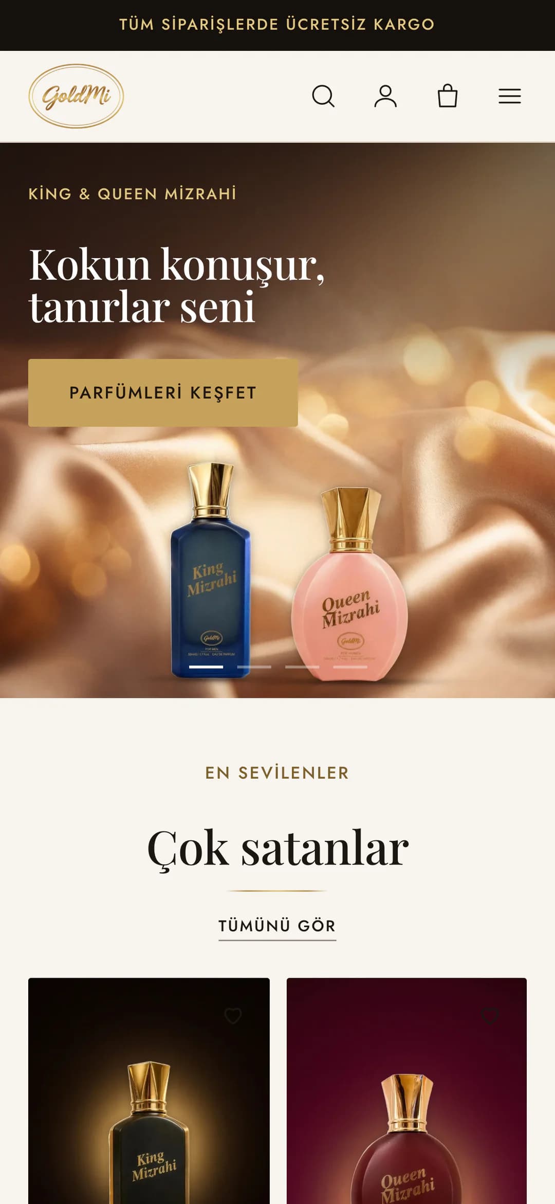 Goldmi'nin telefondaki ana sayfası: koyu duyuru çubuğunda Tüm siparişlerde ücretsiz kargo, GoldMi logosu, arama, hesap, sepet ve menü simgeleri; açılış slaytında King & Queen Mizrahi etiketi, Kokun konuşur, tanırlar seni başlığı, altın renkli Parfümleri keşfet düğmesi ve şampanya rengi saten üzerinde lacivert King Mizrahi ile pembe Queen Mizrahi şişeleri; altta En sevilenler, Çok satanlar başlığı.
