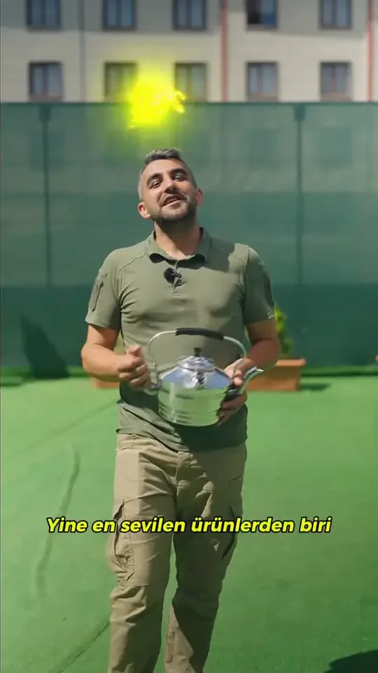 Kamp ve Ötesi video kapağı: çim kaplı bir terasta elinde çaydanlık tutan, haki gömlekli bir kişi ve Yine en sevilen ürünlerden biri altyazısı.