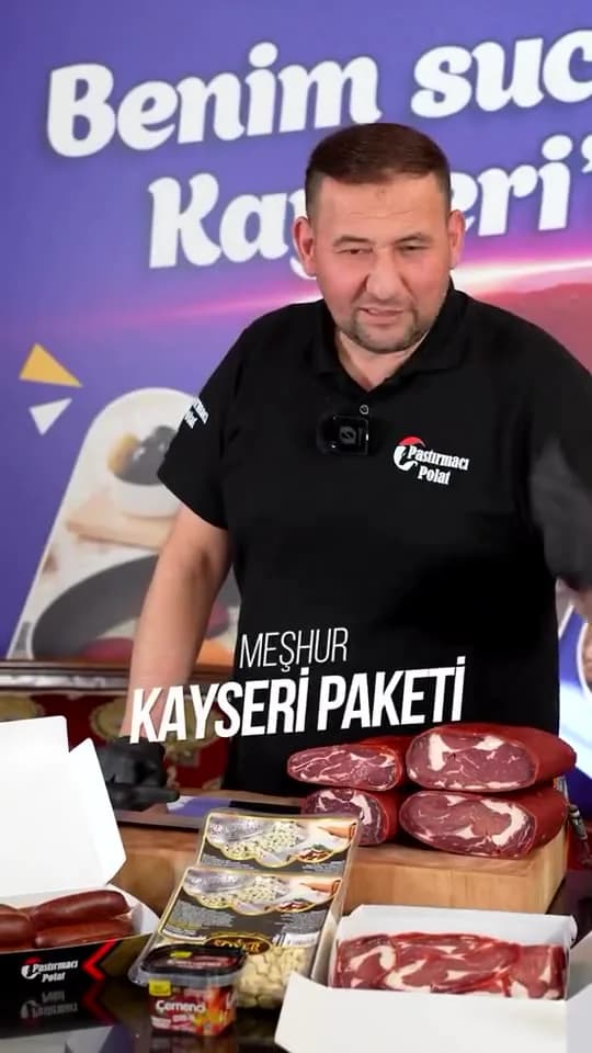Pastırmacı Polat dikey video karesi: tezgâhta markalı kutulara pastırma, sucuk ve mantı yerleştiren usta, üzerinde Meşhur Kayseri paketi yazısı.