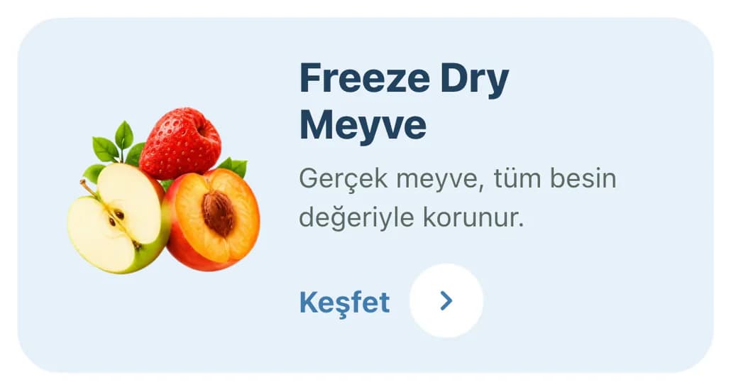 Tam ana sayfasındaki Freeze Dry Meyve keşif kartı telefonda: açık mavi zeminde elma, çilek ve şeftali illüstrasyonu, Freeze Dry Meyve başlığı, Gerçek meyve, tüm besin değeriyle korunur açıklaması ve Keşfet bağlantısı.