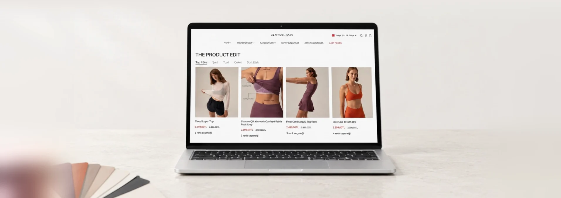 Kamera ön plandaki renk ve yazı tipi kartlarından arkadaki dizüstü bilgisayarda açık Rasquad Shopify mağazasına kayıyor